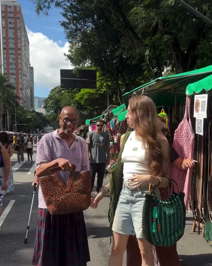 Márgelo na Feira Hippie com uma bolsa de quadradinhos