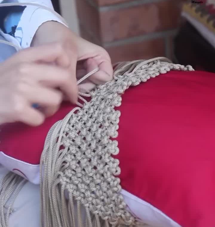 Mãos de uma macrameira fechando os nós de uma bolsa