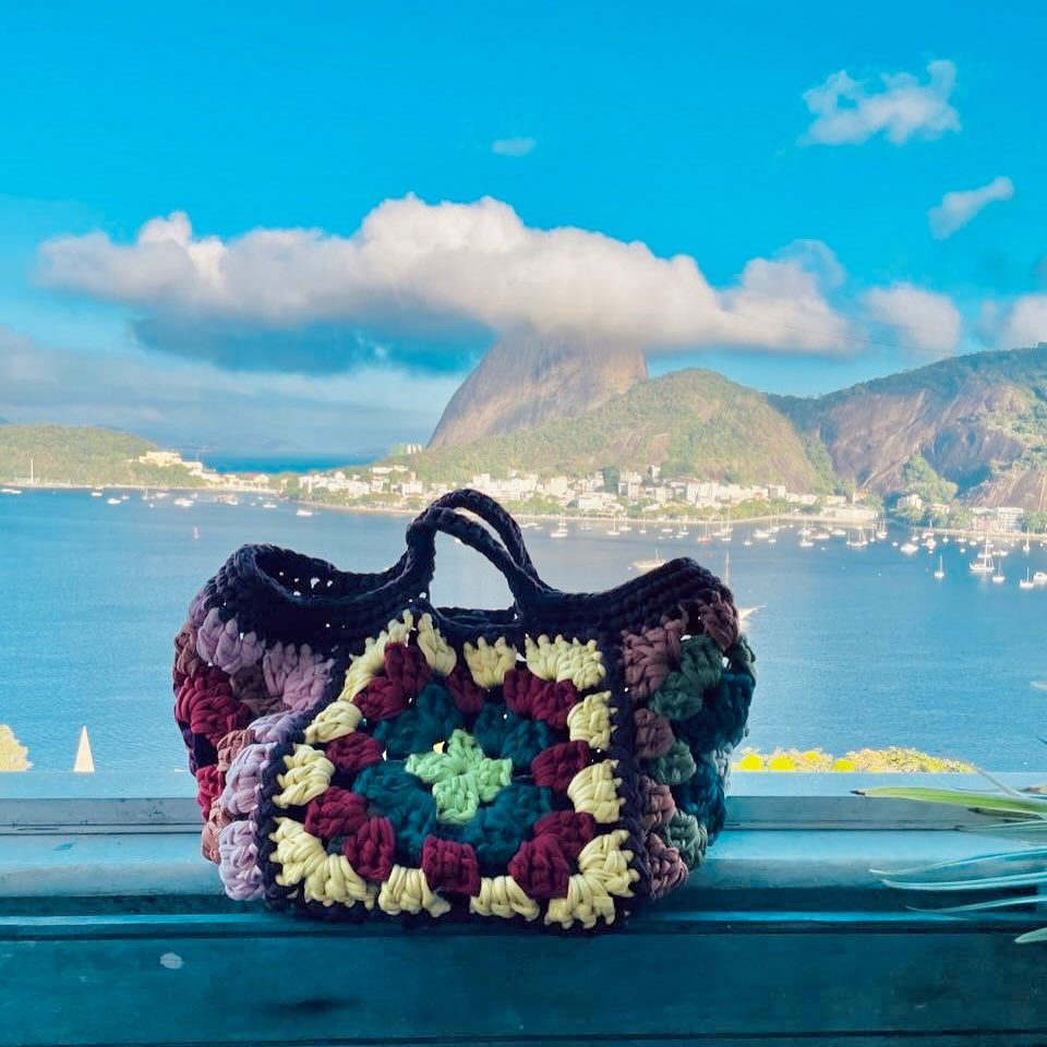 Bolsa de quadradinhos coloridos com o Rio de Janeiro ao fundo